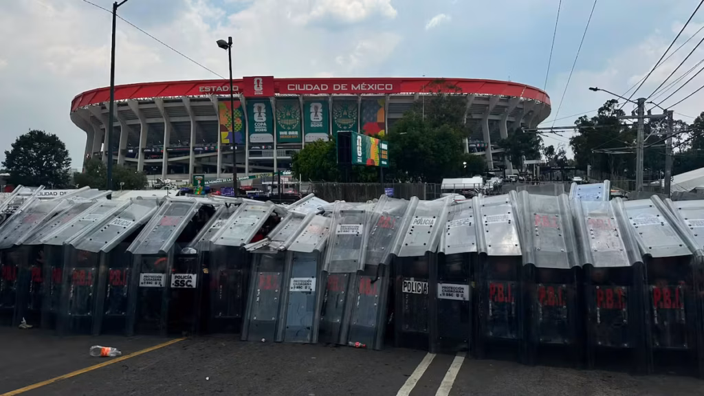 Aficionados con camisetas verdes celebran el Mundial mientras al fondo se observan expresiones sociales en una ciudad mexicana