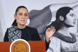 Un micrófono frente a cámaras de televisión con el Palacio Legislativo desenfocado al fondo.